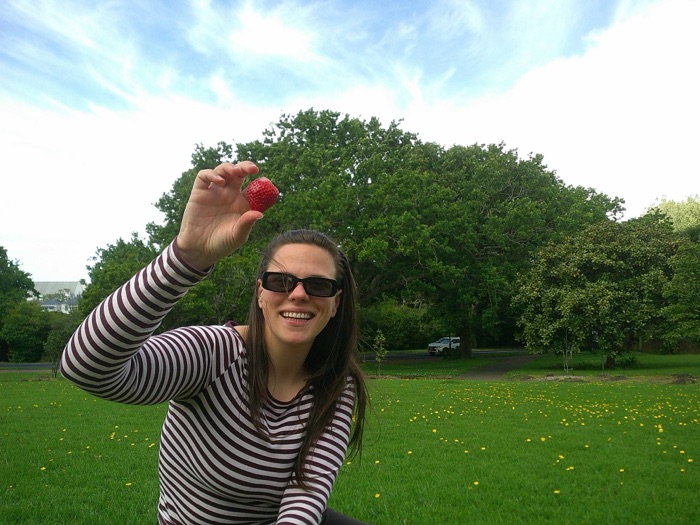 Showing off a strawberry under a big tree
